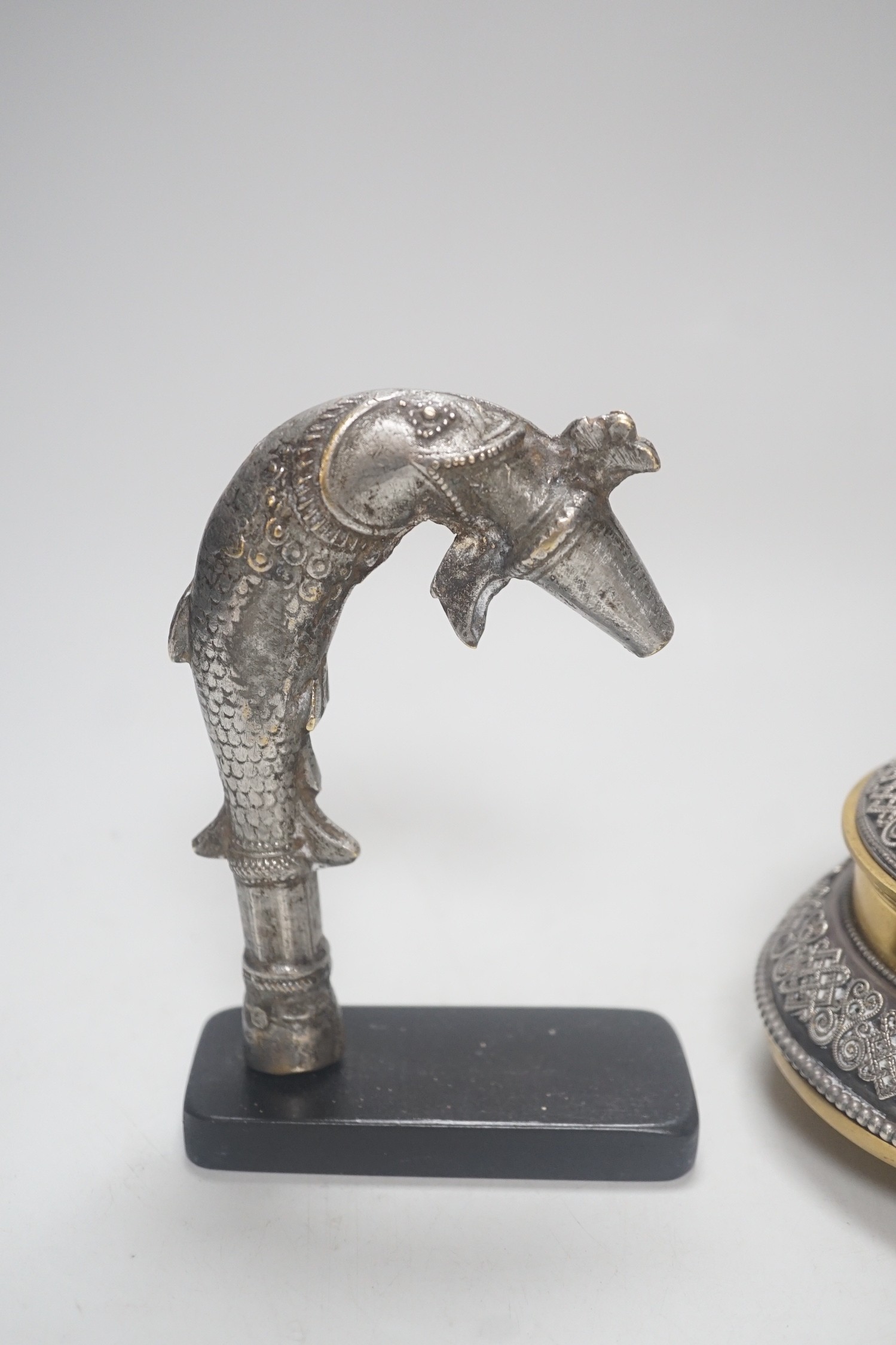 A Continental silvered and gilt metal inkwell, c.1900, and an Indo-Persian silvered bronze ‘fish’ tap or cane handle on stand, 16cm